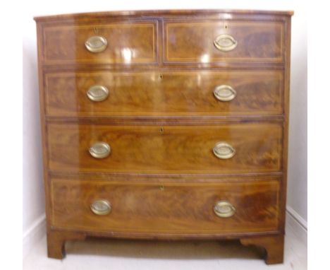 A George III boxwood inlaid mahogany bow front dressing chest, having two short and three graduated long drawers with brass h