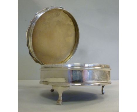 A Victorian style silver circular ring box with an engine turned, hinged lid, enclosing a fabric lined interior, on block fee