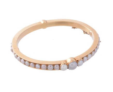 A late Victorian half pearl bangle by Carlo Giuliano, circa 1885, the hinged bangle set with graduated 3.5mm to 7mm pearls, i