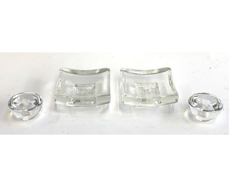 Two Kosta Boda square glass dishes, each 10cm square, together with two glass candle stick holders, marked to base, 3.5cmH 