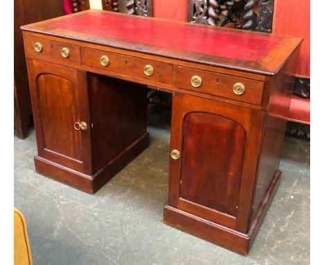 A Victorian mahogany pedestal desk, three drawers over two cupboards, each pedestal with single cupboard door, on plinth base