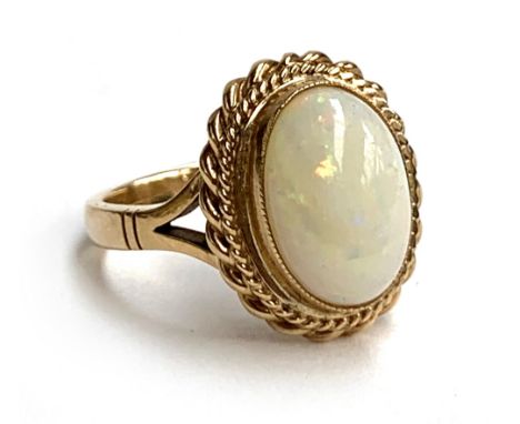 A 9ct gold ring set with an opal cabochon with a rope twist border, size P, 6.1g 