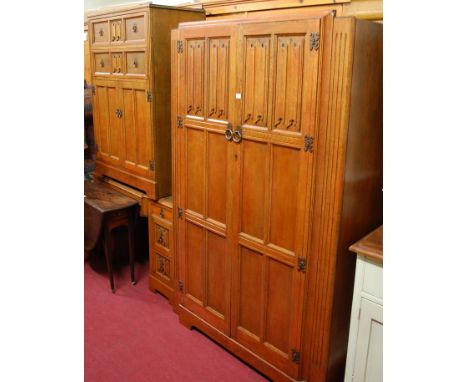 A late Arts & Crafts oak linenfold panelled bedroom suite, comprising; double door wardrobe, having interior mirror, hanging 