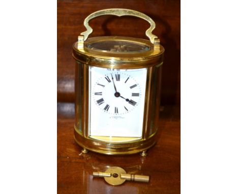 Wilson & Gill, Regent Street, a lacquered brass ovoid five window eight-day carriage clock raised on turned feet with white e