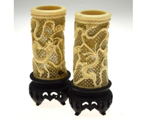 A pair of Chinese reticulated tusk vases, finely worked with dragons amongst clouds, on ebonised wood bases, 15 cm, early 20t