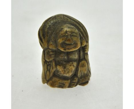 A Japanese bone netsuke carved as Hotei carrying his lucky bag, 4 cm h.