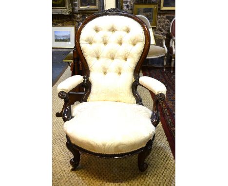 A Victorian carved walnut button-backed elbow chair with concave overstuffed seat
