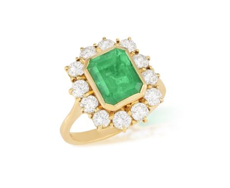 AN EMERALD AND DIAMOND CLUSTER RING  The rectangular-cut emerald weighing approximately 2.80cts within collet-setting, to a b