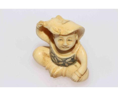 Ivory netsuke of seated child with adult mask.