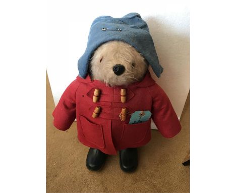 A Gabrielle Designs Paddington Bear soft toy, with label, in blue hat, red duffel coat (holes), with luggage label and blue D