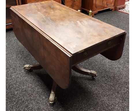 A Georgian drop end sofa table, designed with a heavy wooden turned pedestal, off set by metal mounted legs. [72x121x112cm] 