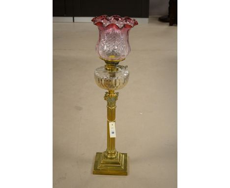 A late 19th century oil lamp, with pink glass shade, cut glass reservoir and brass corinthian column stand.