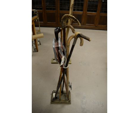 Six walking sticks, to include horn handles; together with a shooting stick; and a brass stand