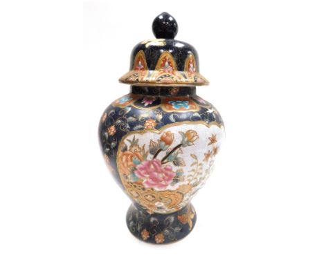 A 20thC Chinese famille noire jar and cover, decorated with reserves of flowering branches, against a dark blue ground with f