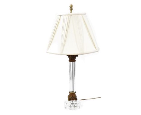 A glass column table lamp, with gilt metal Corinthian capital and octagonal base, with pleated silk shade and simulated ivory