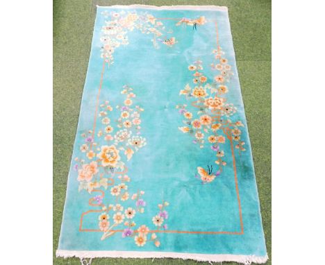 A Chinese wall rug, decorated with flowers, on a jade green ground, possibly 1920s, 118cm x 207cm. 