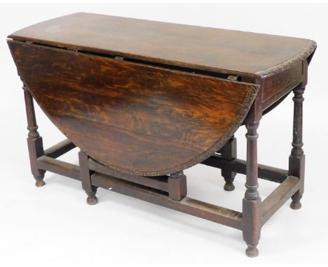 An 18thC oak drop leaf gate leg dining table, the top with a carved border, raised on turned legs, united by a box stretcher,