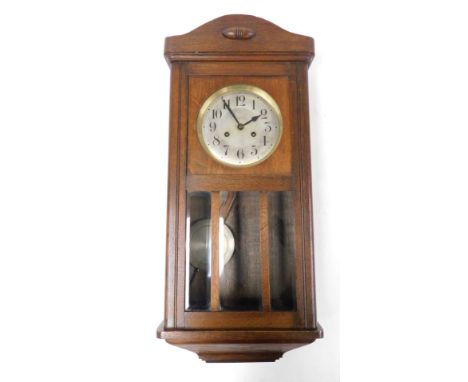 An early 20thC oak cased wall clock, the silvered Arabic numeral dial with brass chapter ring and eight day movement, with ke