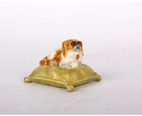 A ROYAL WORCESTER MINIATURE MODEL OF A KING CHARLES SPANIEL ON A CUSHION, 4CM L, PUCE PRINTED MARK, 1907. 