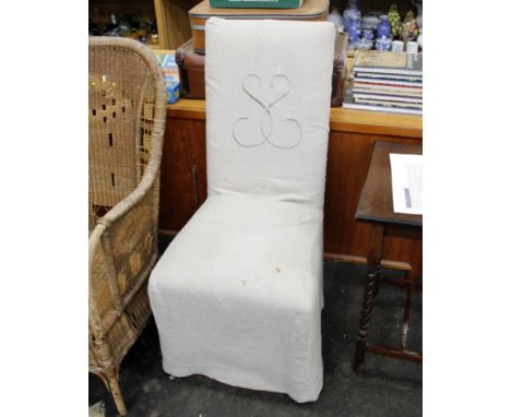 A straight backed bedroom chair upholstered in orange silk, with protective button over cream linen cover