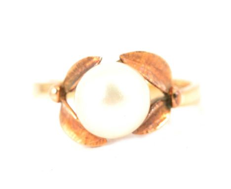 A cultured pearl dress ring, the 8.5mm pearl peg set on an all yellow metal mount with leaf surround, ring size N, shank mark