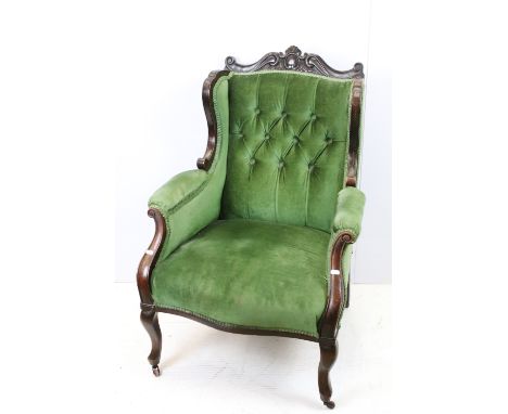 Victorian mahogany armchair, with carved top rail, upholstered in green with button back, on cabriole legs and castors, 97cm 