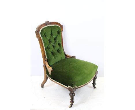 Edwardian nursing chair, with carved back, upholstered in green with button back, on turned legs and castors, 90cm high x 58c
