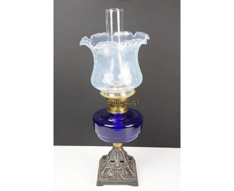 Early-to-mid 20th C oil lamp with opalescent flared glass shade, chimney, cobalt blue glass font and pierced cast iron base. 