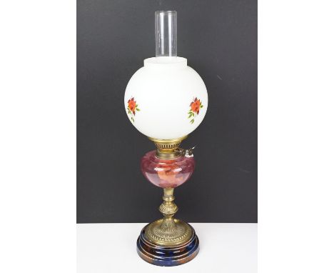 Early 20th century brass oil lamp, the white glass shade with floral detail, with cranberry glass font, and glass chimney, th
