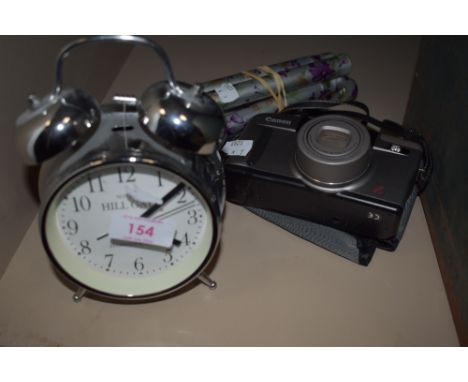 A canon Z135 film camera, a collapsible walking stick and an alarm clock.