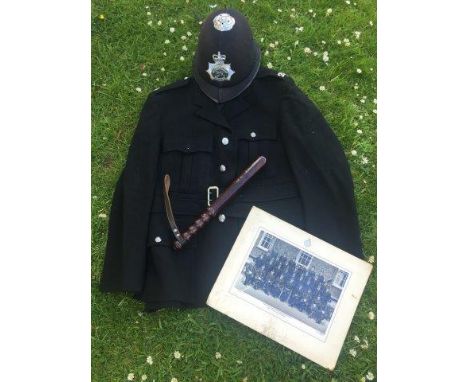 A Metropolitan Police jacket, a Metropolitan Police helmet, a wooden truncheon and an early black and white photograph of the
