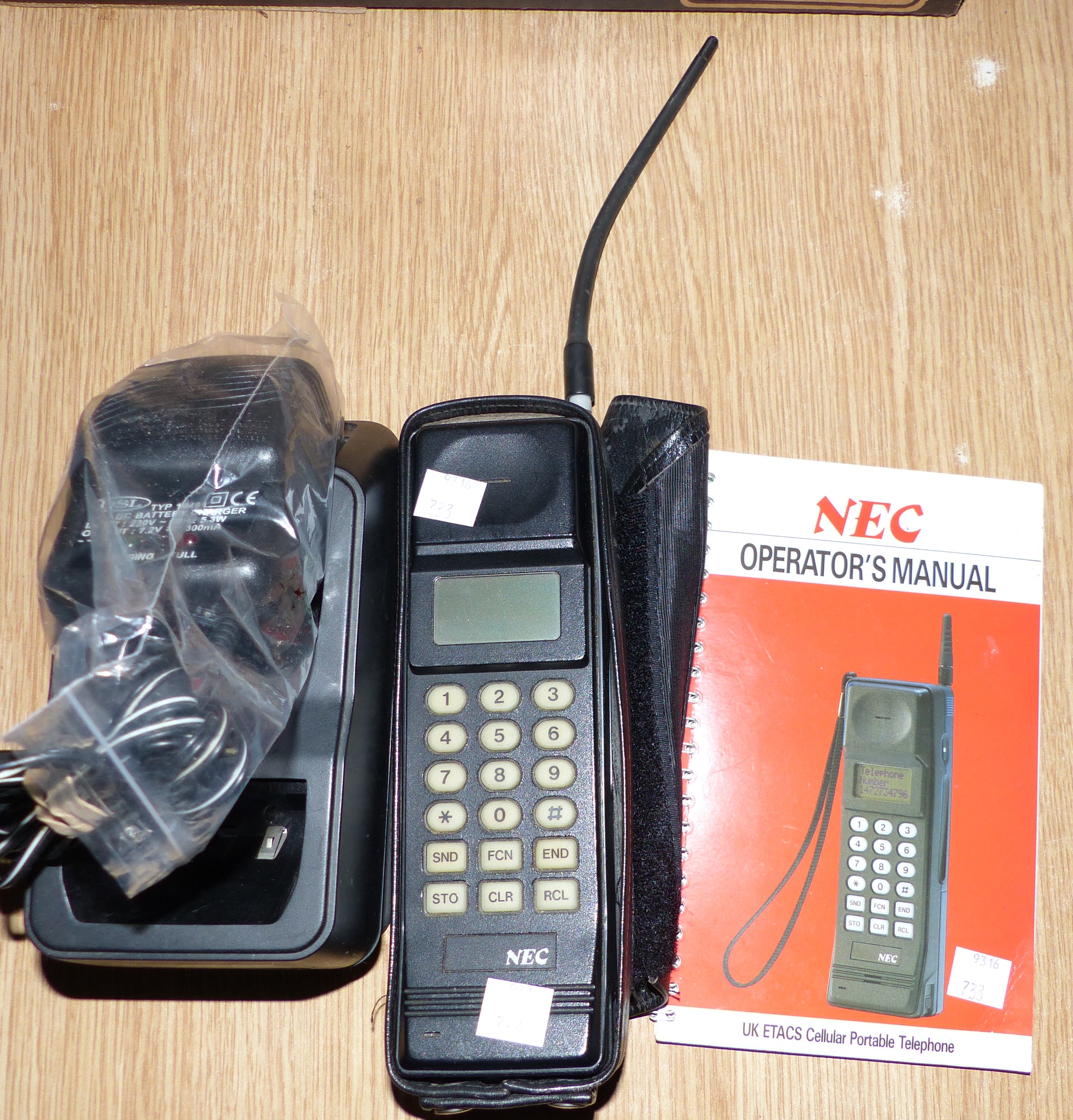 An NEC UK ETACS Cellular Portable Telephone with charging unit and handbook