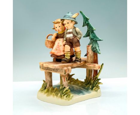 A figure of a young girl and boy walking over a bridge that is located above a river and some greenery. Goebel Hummel backsta
