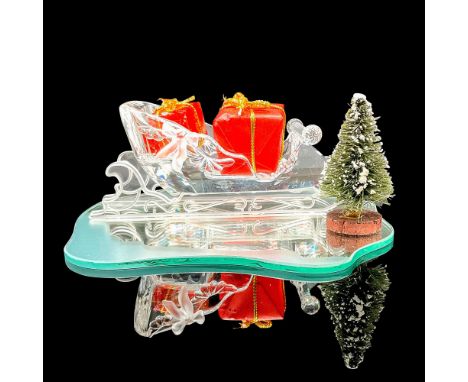 Faceted and molded crystal figurine modeled as a sleigh decorated with crystal scrolls and ribbons. Includes two red presents