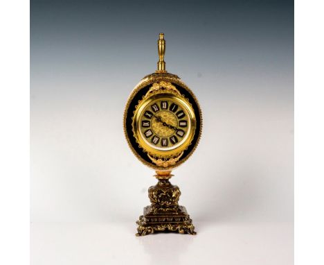 Ornamental clock embellished with gold-tone detailing, lined with black fabric exterior and purple fabric interior. Detailed 