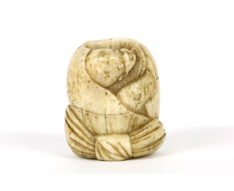 A 19th century bone netsuke, carved as a Chinese boy climbing out of a bag tied with a bow, infill missing, 3.8cm