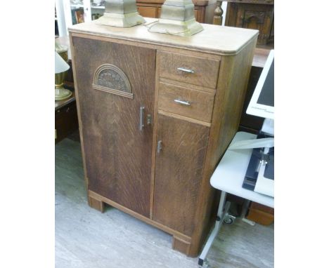 A 1930s oak tallboy, having two doors and two short drawers, raised on bracket feet  52''h  32''w       LAF