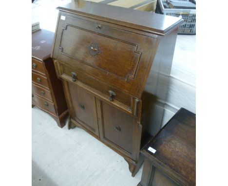 A 1930s oak bureau, having a fall front, over a drawer and two panelled doors, raised on bracket feet  40''h  29''w        BS