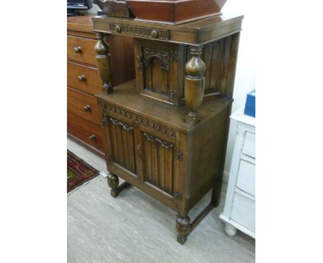 A 1930s oak court cupboard, the top having a frieze drawer, over an arched panelled door and two linen fold panelled doors, r