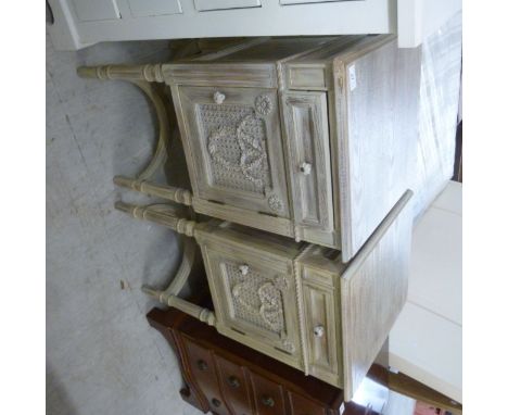 A pair of modern French grey washed bedside cabinets, each having a drawer, a woven caned panel and foliate carved door, rais