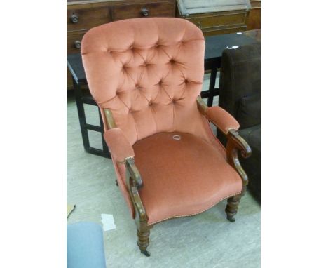 A late Victorian mahogany framed salon chair, having a red fabric button upholstered back and swept open arms, raised on turn
