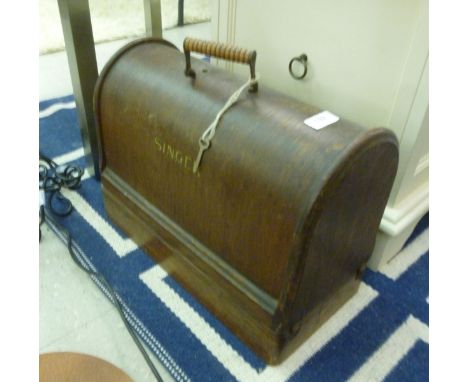 A Singer manual sewing machine, in an oak finished carrying case         CS