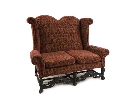A Queen Anne style sofa upholstered in a red and green foliate fabric, on carved supports, united by a stretcher,162cm wide89
