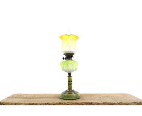 A Victorian moulded green glass oil lamp with a graduated etched glass shade, and a central glass chimney, over a green mould
