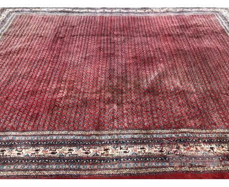 An oriental carpet, the central red ground decorated with a dense pattern of geometric shapes within a multiple banded border