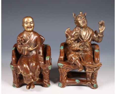 China, two glazed ceramic figures of Taoist gods, 20th century, both seated in a throne, the figures in typical dress and wit