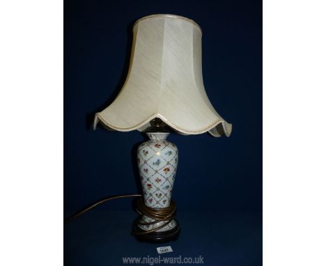 A pretty china lamp base decorated with painted flowers on wooden base with cream shade, base 13" tall, incl. shade 25" tall.