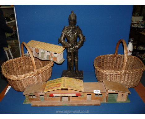 A wooden model of a saloon, a model of stables, tin plate model of a standing knight and two wicker baskets.