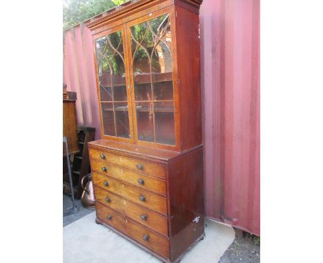 A George II mahogany bookcase cabinet having moulded cornice over twin glazed doors, above a secretaire drawer and three long