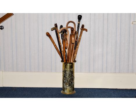 Brass Embossed Stick Stand containing a collection of approx 16 walking canes. All ages and mixed varieties, some carved.